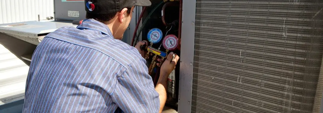 HVAC technician servicing a condenser unit in Weston